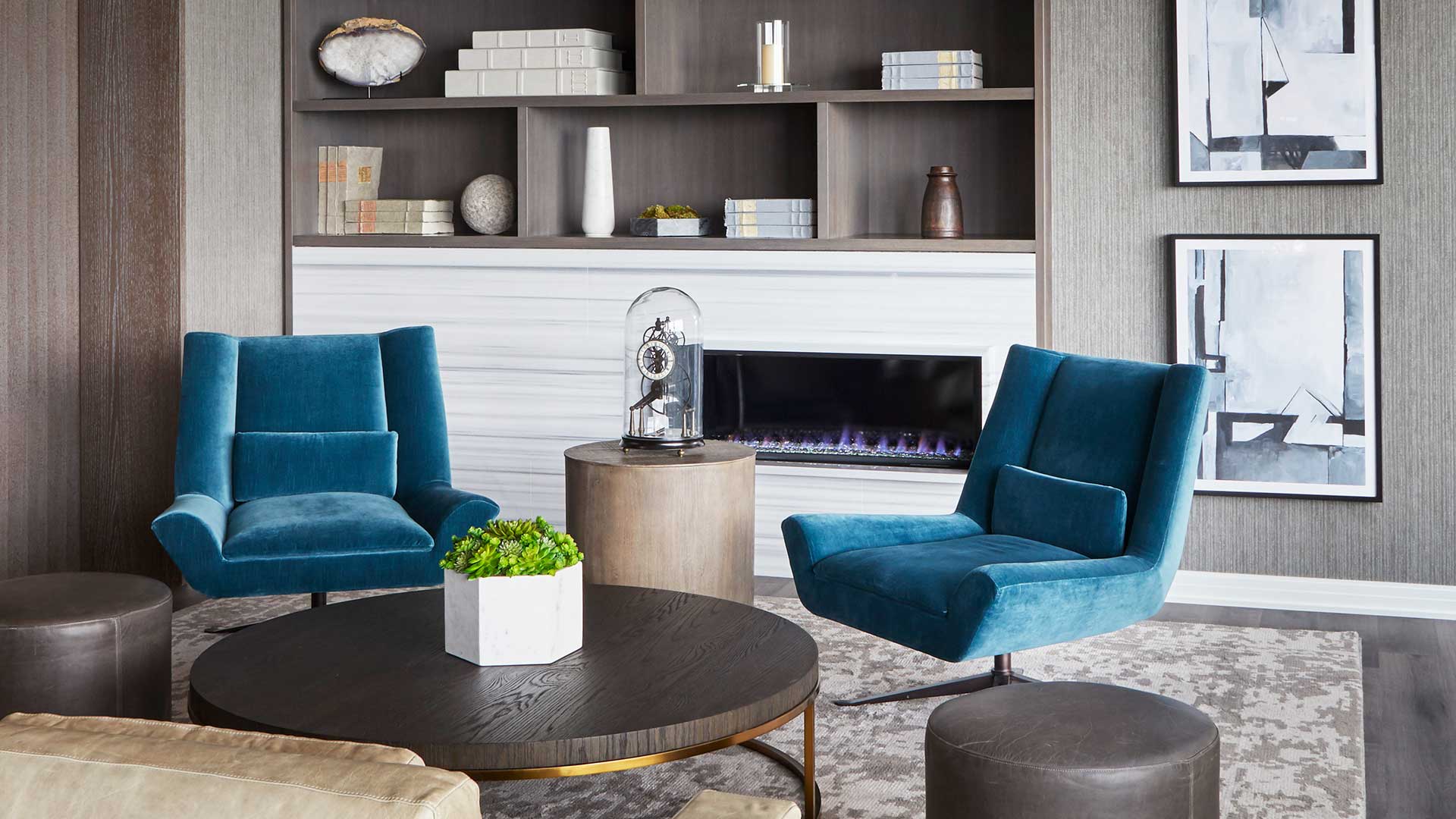 Club furniture around a round coffee table. A built-in bookshelf and fireplace are behind.