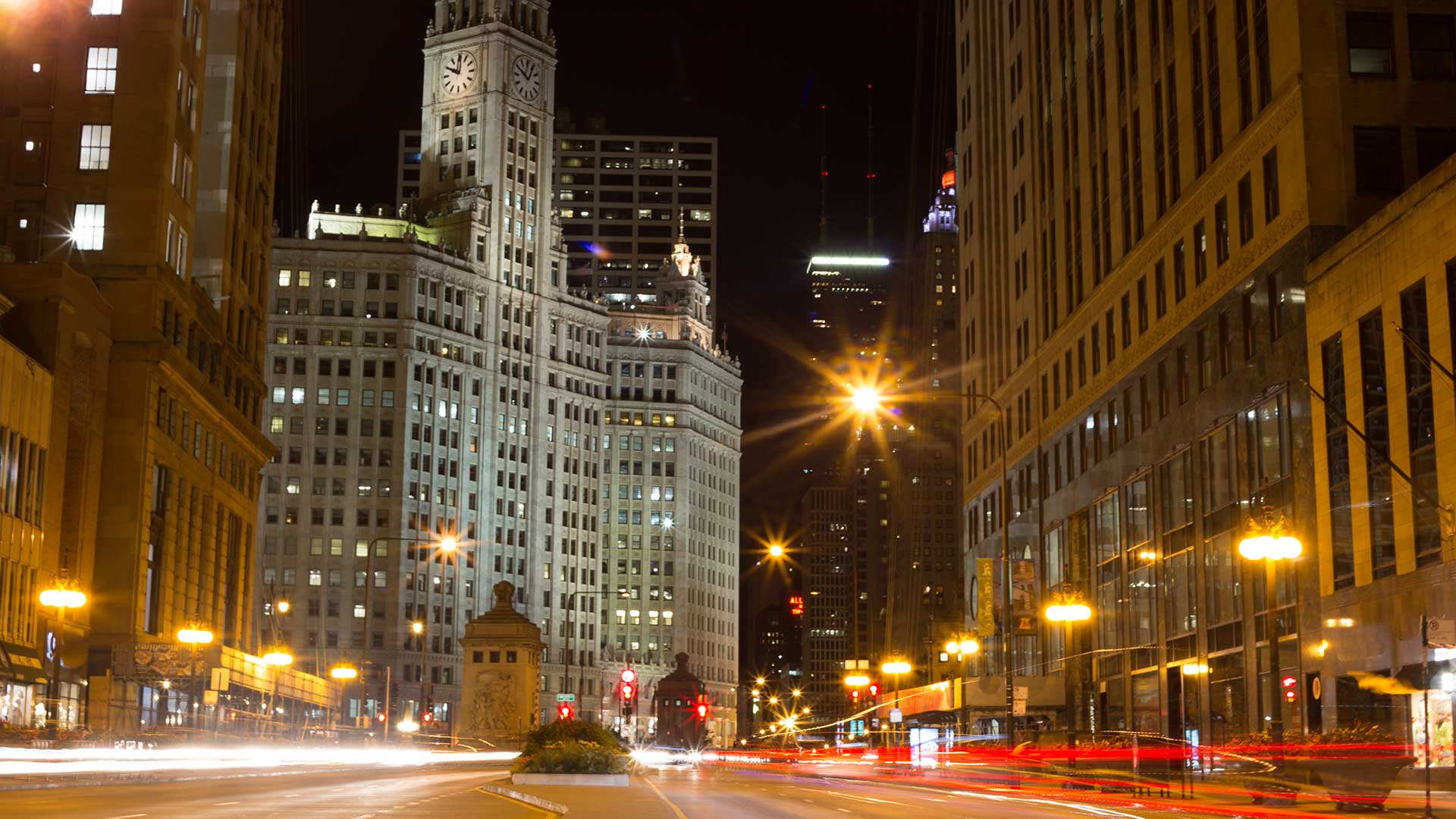 Looking down Michigan Avenue in Chicago at night. A time lapse shows cars coming and going in streaks of red and white light.